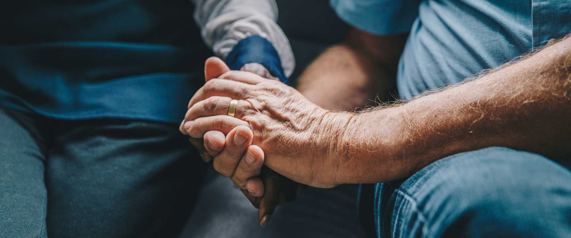 Elderly man holds the hand of a younger person