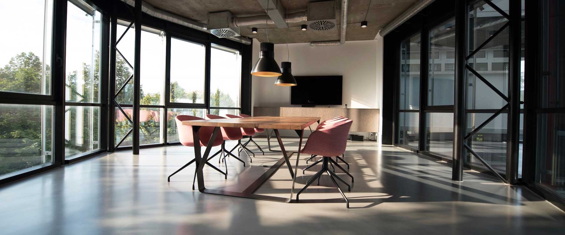 Empty worktable with 3 rose-coloured chairs on each side in a modern-looking conference room